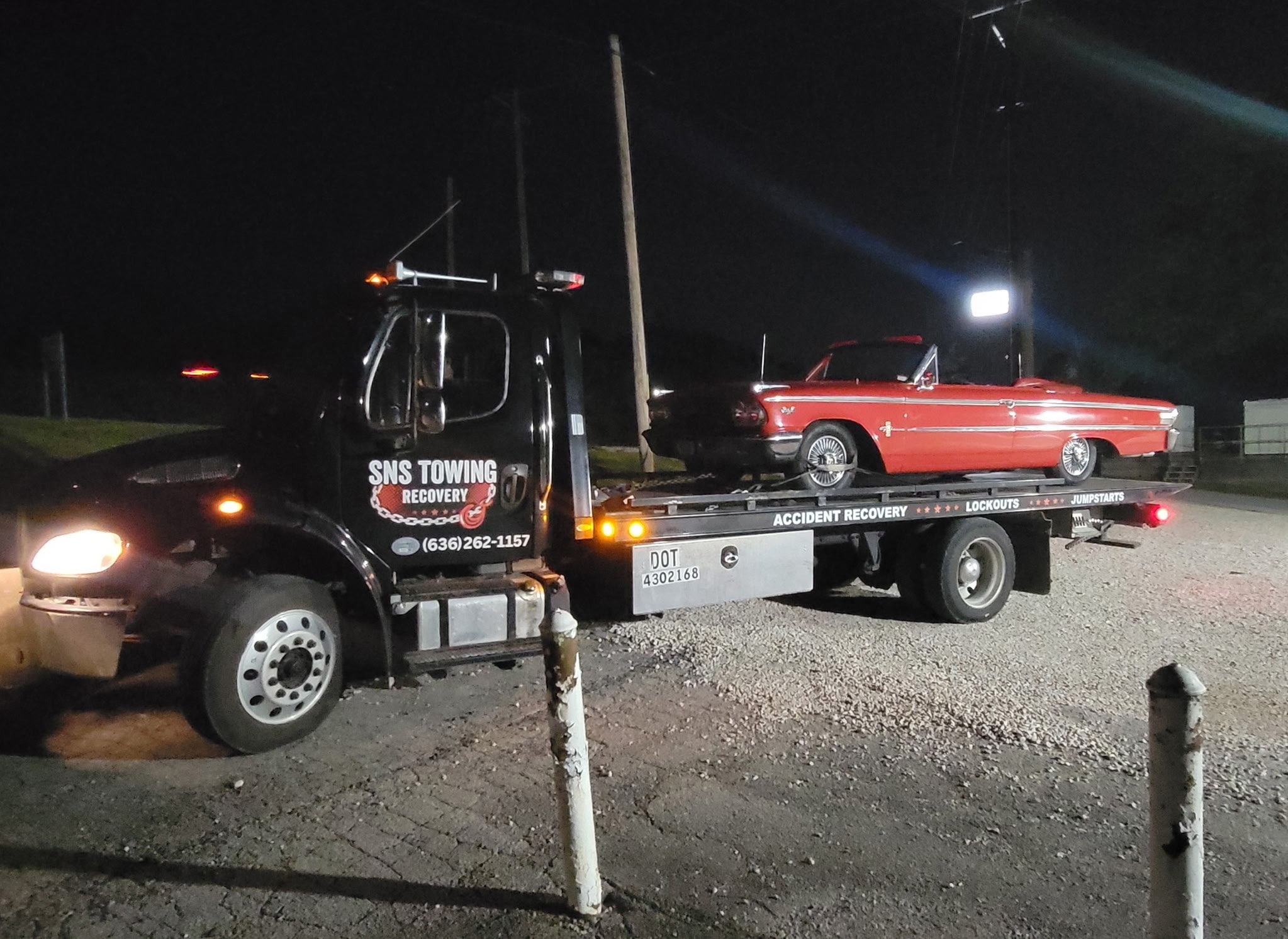 SNS Towing black truck carrying white Bentley convertible in residential neighborhood